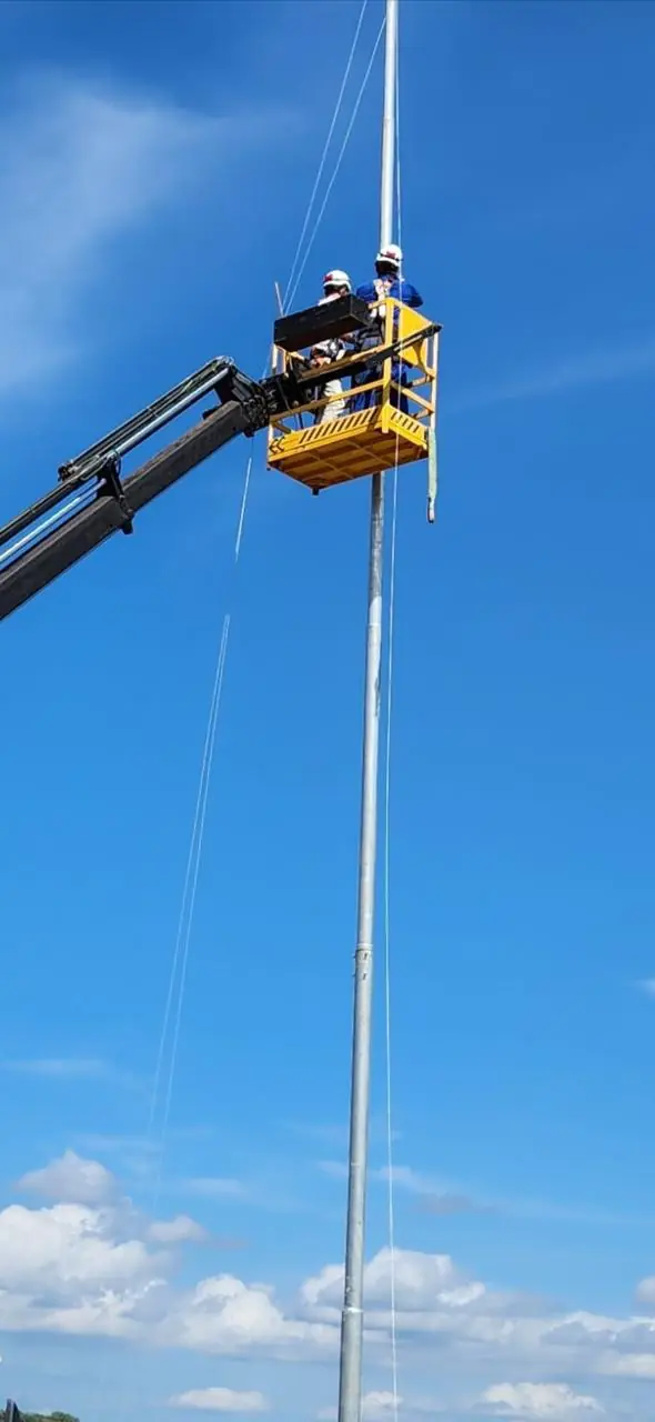 Cesto aéreo acoplado ao Munck em trabalho no alto de um poste