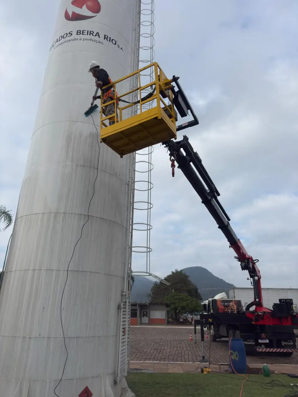 Cesto aéreo no caminhão Munck em limpeza de silo industrial